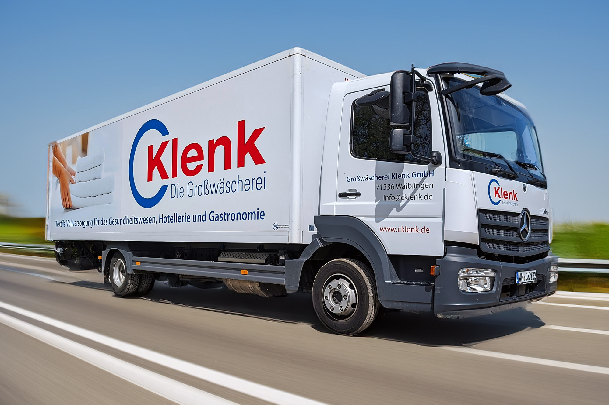 Ein Lastwagen fährt die Straße entlang, mit dem Schriftzug "CKlenk" auf der Seite.
