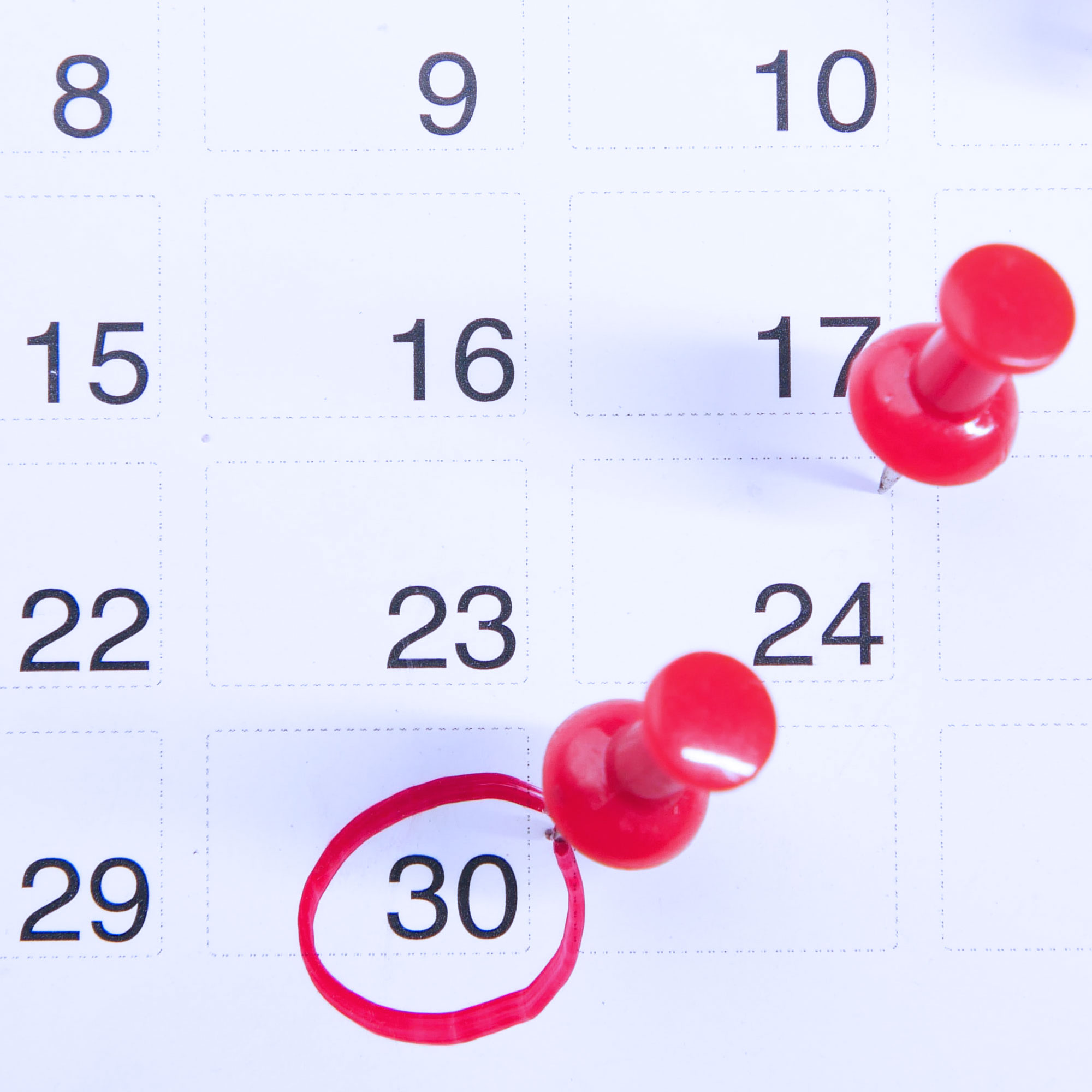Kalenderblatt mit roten Pin-Nadeln und rot umkreisten Zahlen